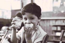 Primer plano de niño comiendo un yogurt y una manzana en su colegio