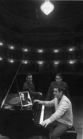 Trabajadores del teatro municipal junto a un piano de cola, con una foto de Arrau, Claudio