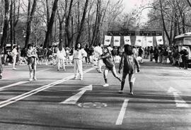 Jóvenes y niños vestidos para hacer deportes, en la calle que bordea al parque forestal