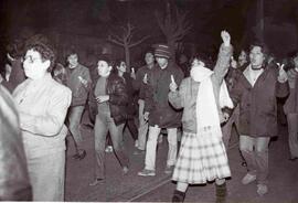 Multitud de personas, caminando por una calle, cantando una canción