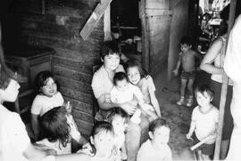 Muchos niños en una casa de población, jugando y sonriendo a la cámara