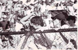 Galería de estadio con dos hinchas agarrados a una reja, gritando