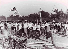 Manifestantes avanzan junto a una barricada en llamas