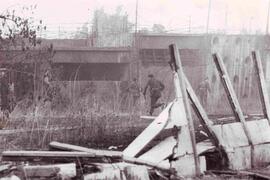 Carabineros buscando a una persona, corriendo por debajo de un puente desolado