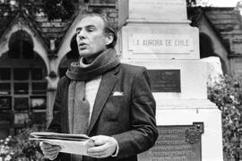 Plano medio de Lavandero, Jorge leyendo un discurso en el Cementerio general, con una placa de la...