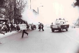 Manifestación en pro de los derechos humanos en donde las personas arrancan de las bombas lacrimó...