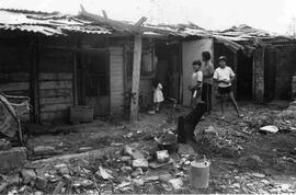 Niños afuera de una casa muy pobre, mirando a la cámara