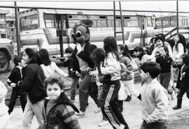 Niños caminando junto a una persona disfrazada de ratón